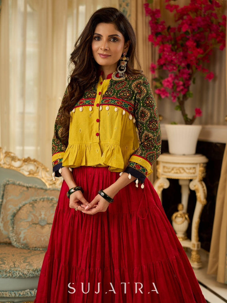 Red tiered Jamdani lehenga with a striking green Ajrakh and mustard jamdani choli featuring intricate mirror work & shell tassels .