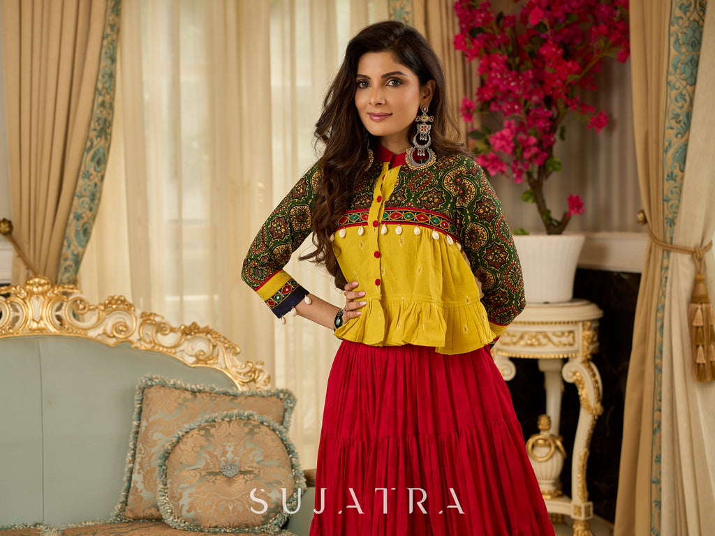 Red tiered Jamdani lehenga with a striking green Ajrakh and mustard jamdani choli featuring intricate mirror work & shell tassels .