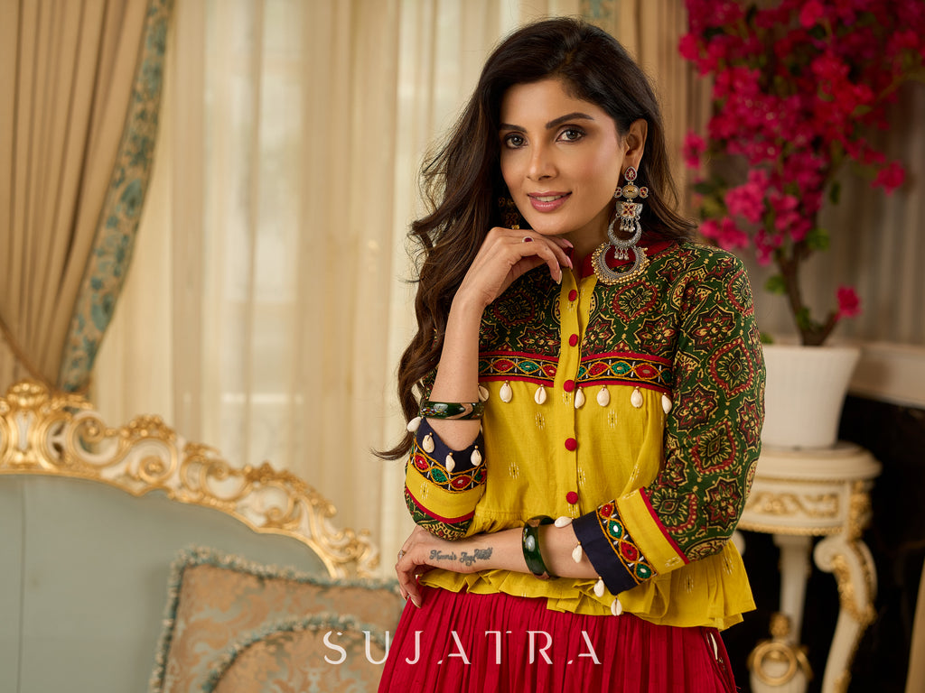 Red tiered Jamdani lehenga with a striking green Ajrakh and mustard jamdani choli featuring intricate mirror work & shell tassels .