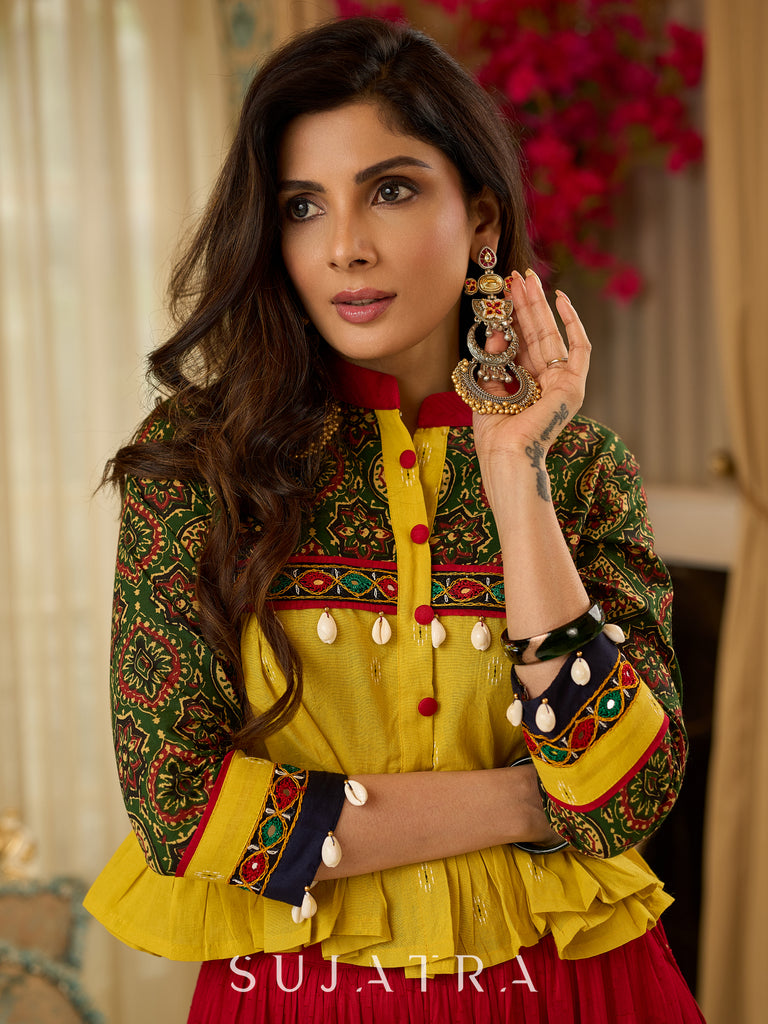 Red tiered Jamdani lehenga with a striking green Ajrakh and mustard jamdani choli featuring intricate mirror work & shell tassels .