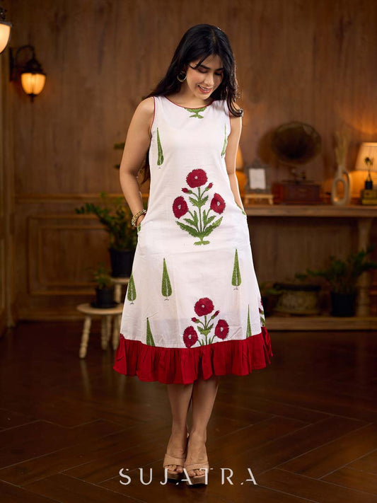 White sleeveless dress featuring red butta motifs and a gathered red panel at the hem, finished with coordinated red accents for a fresh, playful silhouette with a touch of traditional charm.