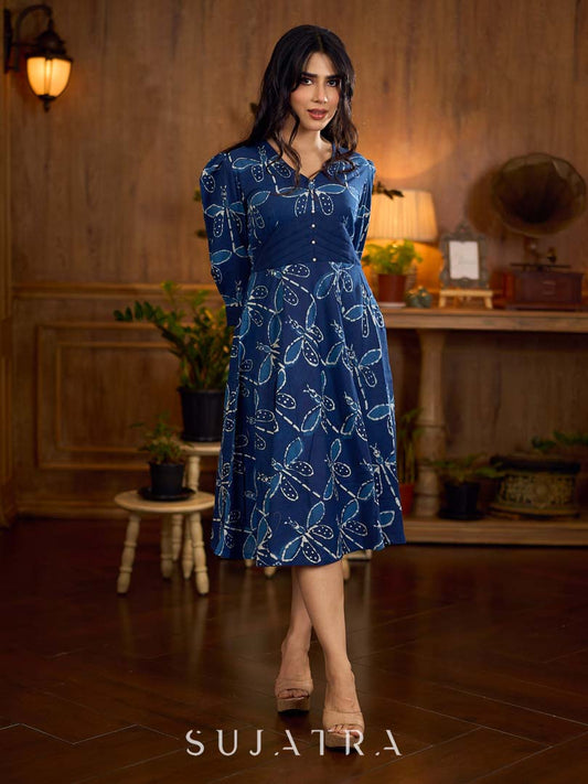 Indigo printed dress featuring dragonfly motifs, gathered sleeves with cuffs, and navy blue pleated waist detailing accented with pearls, creating a graceful silhouette with refined artisanal charm.