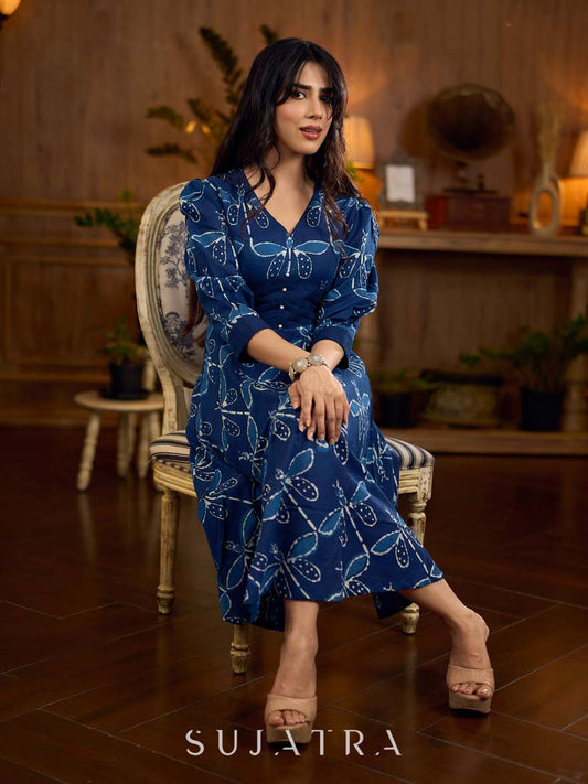 Indigo printed dress featuring dragonfly motifs, gathered sleeves with cuffs, and navy blue pleated waist detailing accented with pearls, creating a graceful silhouette with refined artisanal charm.