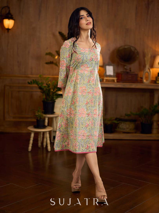 Soft green Gulmohar-printed dress featuring a square neckline and pearl-highlighted motifs, finished with an elasticated waist to create a flattering cinched silhouette with effortless charm.