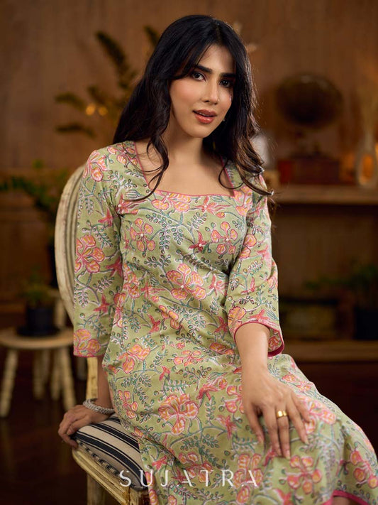 Soft green Gulmohar-printed dress featuring a square neckline and pearl-highlighted motifs, finished with an elasticated waist to create a flattering cinched silhouette with effortless charm.