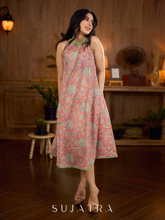 Soft peachy pink floral halter-neck dress with fresh green accents, crafted in a bias-cut silhouette that creates graceful flow and a fluid drape for an effortless summer look.