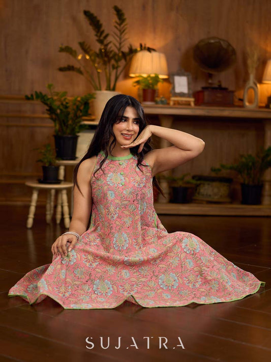 Soft peachy pink floral halter-neck dress with fresh green accents, crafted in a bias-cut silhouette that creates graceful flow and a fluid drape for an effortless summer look.