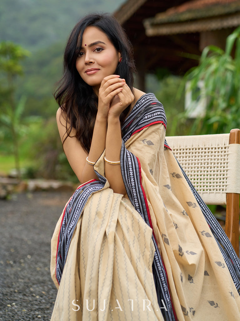 Beige cotton saree enriched with traditional Ikat border and Jamdani accents