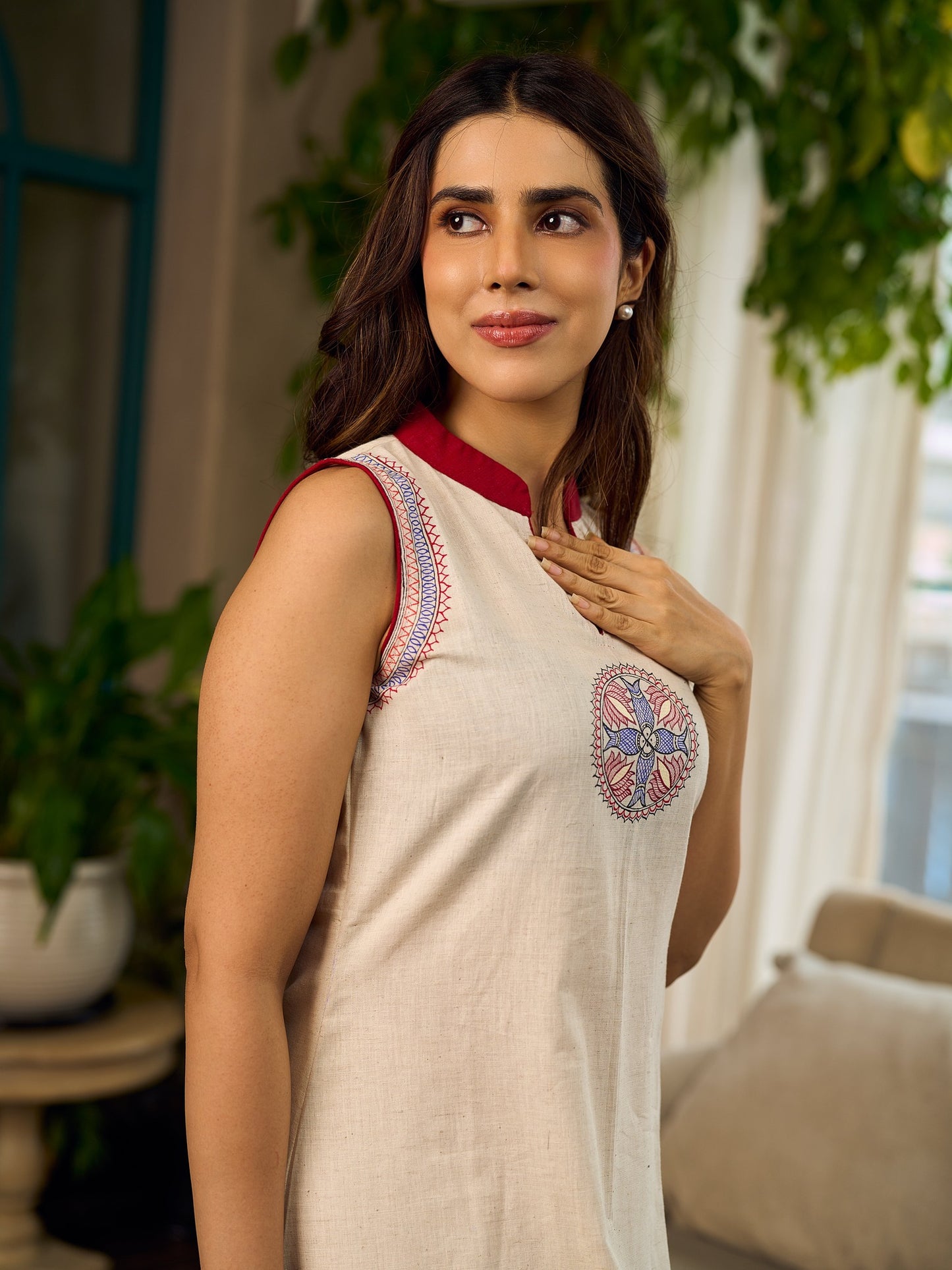 Off-white dress featuring intricate Madhubani artwork and a maroon Mandarin collar.