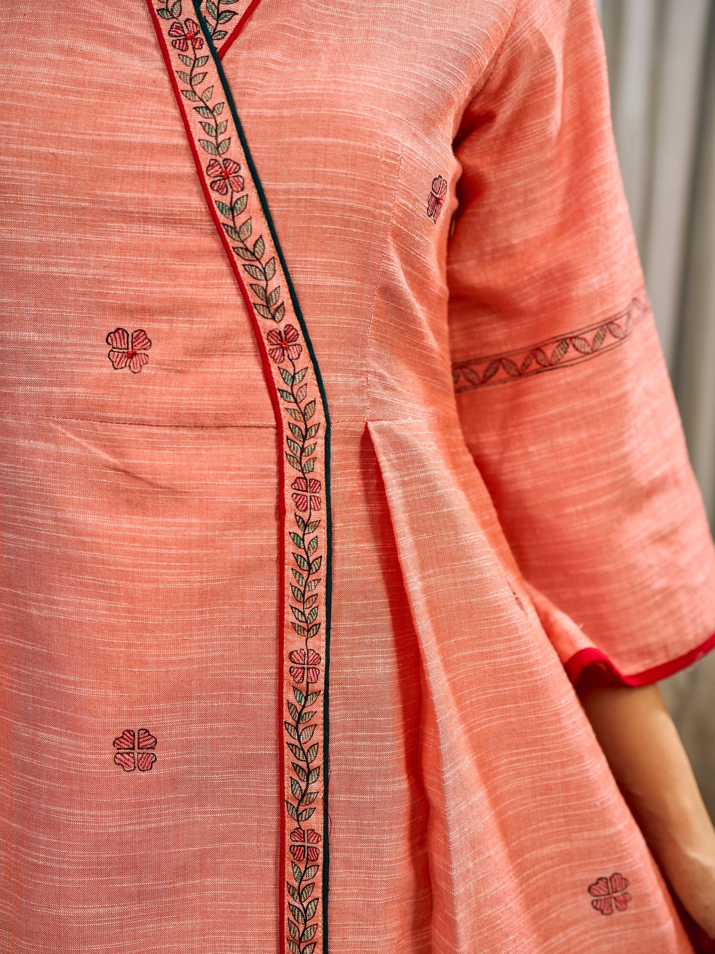 Peach dress featuring delicate Madhubani painting and graceful flared sleeves.