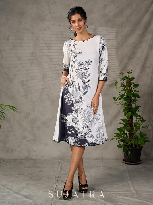 White and black floral dress with pearl embellishments and black accents.