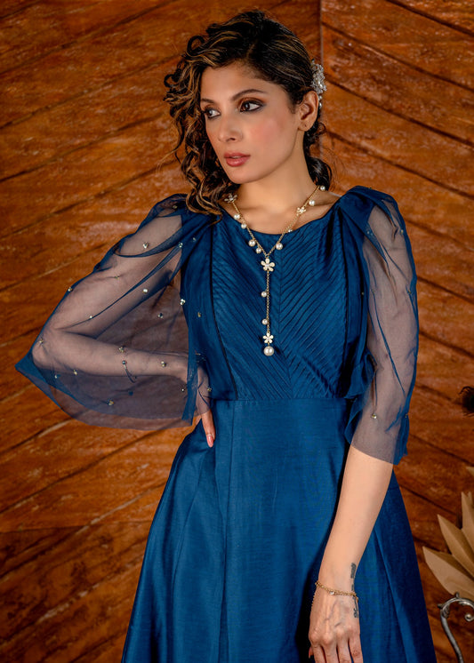Blue satin gown with net sleeves, sequence work & self tucks on yoke.