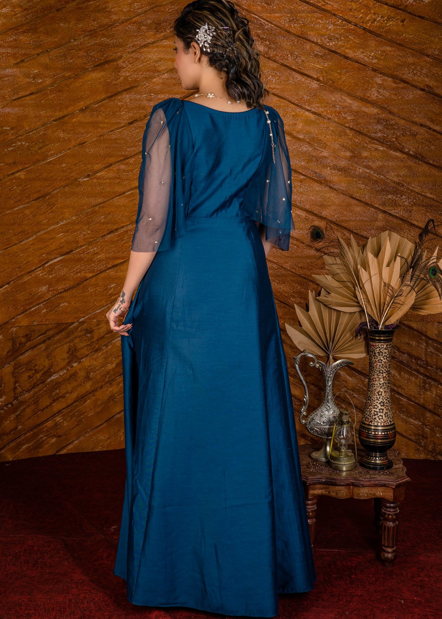 Blue satin gown with net sleeves, sequence work & self tucks on yoke.