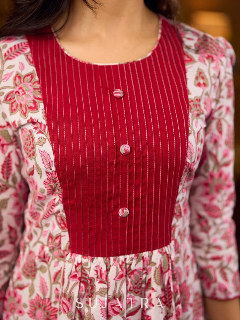 Elegant white floral Jaipuri printed dress with a delicately pintucked red panel, gathered sleeves, and rich red accents.
