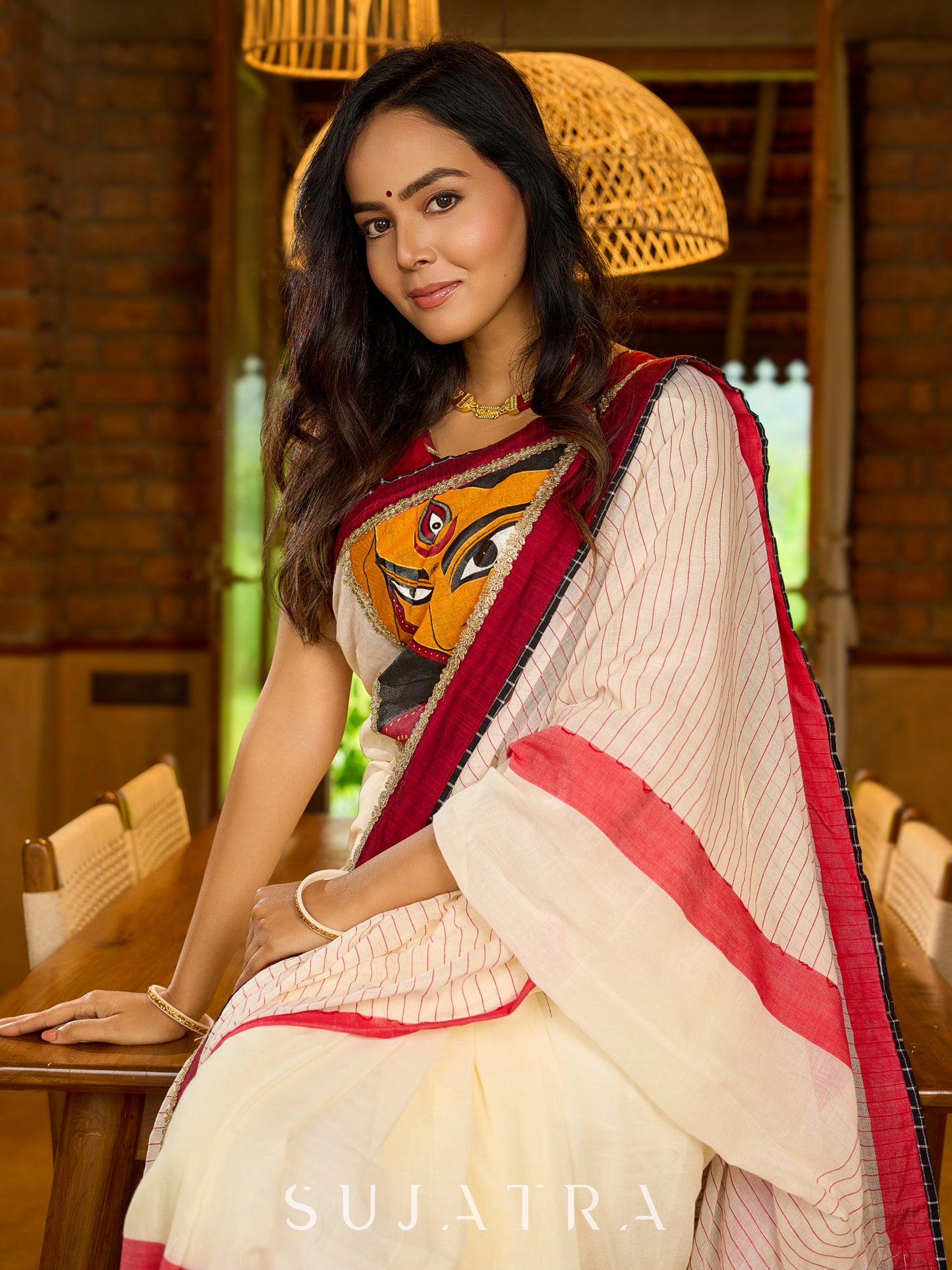 Striking white cotton saree with bold red-black borders, featuring a hand-painted Durga motif