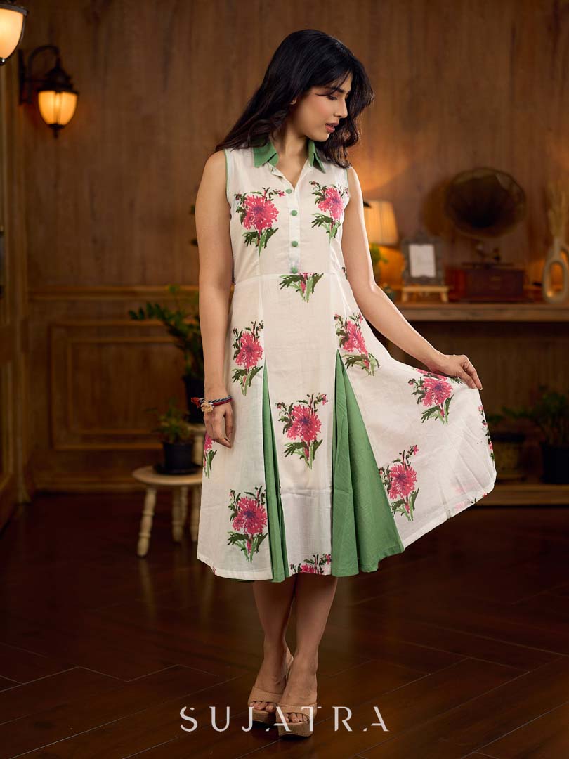 White floral printed sleeveless dress featuring fresh green accents, a structured shirt collar with contrast buttons, and a panelled silhouette with inner green pleats for added flow and movement.