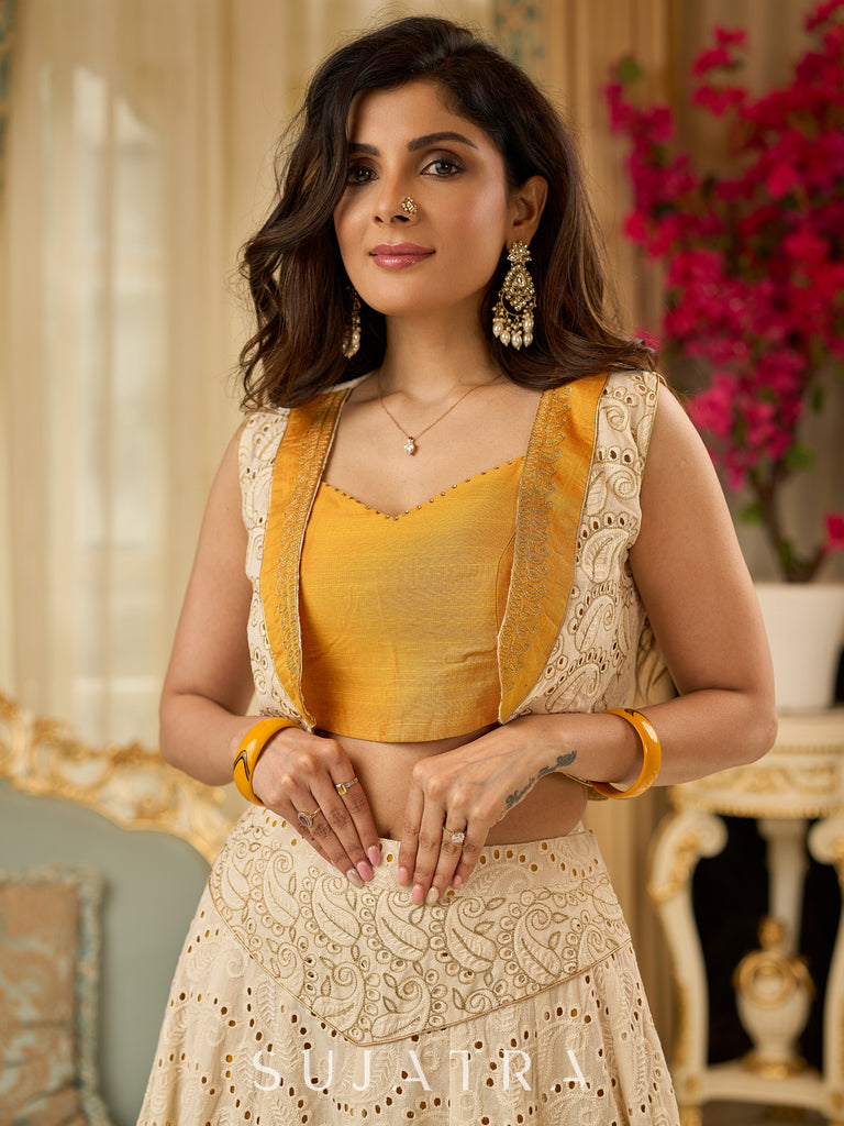 A chic off-white Hakoba Lehenga with intricate gold embroidery accented by a bold, saffron yellow blouse - Gold embroidered hakoba Shrug Optional
