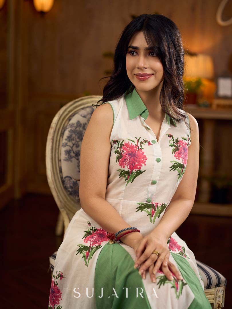 White floral printed sleeveless dress featuring fresh green accents, a structured shirt collar with contrast buttons, and a panelled silhouette with inner green pleats for added flow and movement.