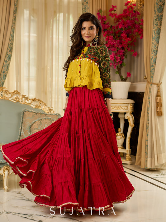 Red tiered Jamdani lehenga with a striking green Ajrakh and mustard jamdani choli featuring intricate mirror work & shell tassels .
