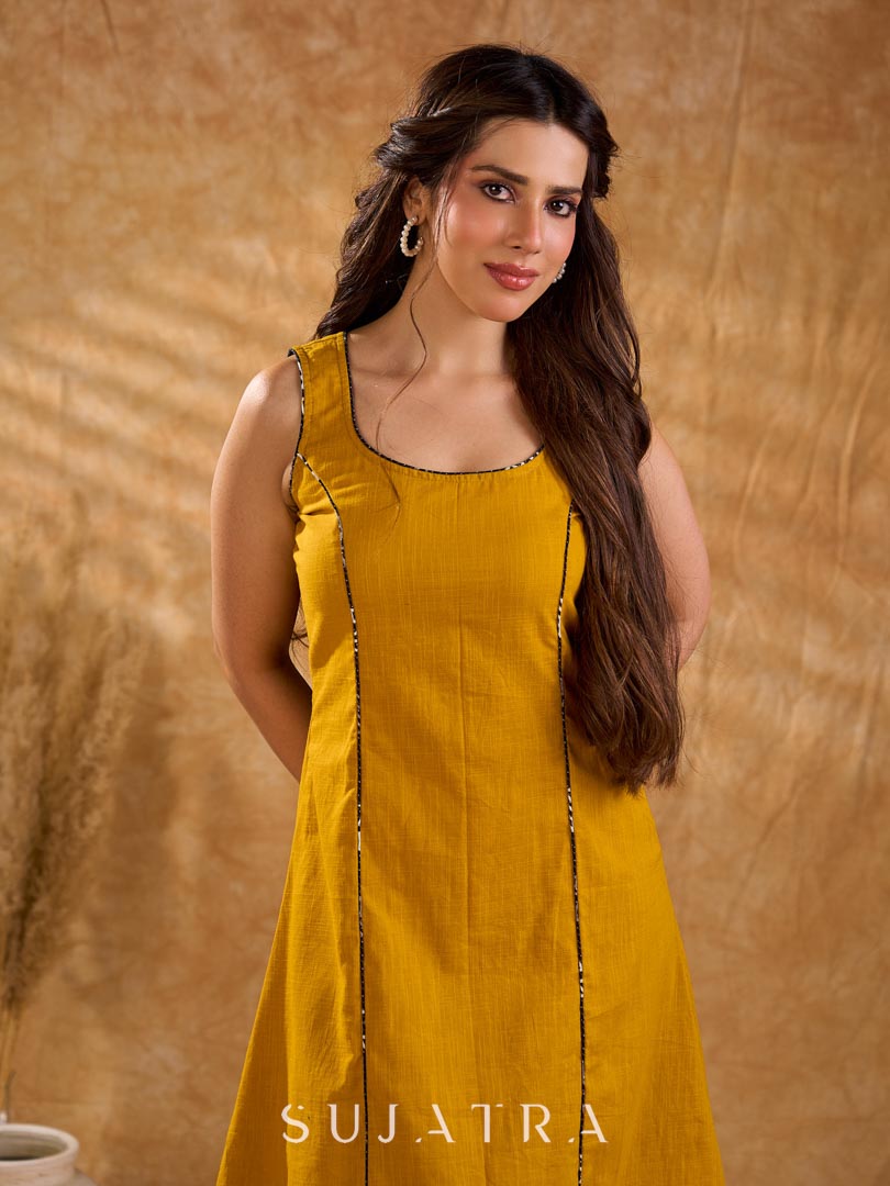 Warm mustard one-piece dress with panelled construction for fluid movement, a sleeveless silhouette, and Kantha cord piping, offering a graceful, well-defined shape with subtle texture and refined detail.