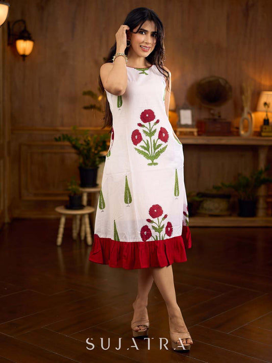 White sleeveless dress featuring red butta motifs and a gathered red panel at the hem, finished with coordinated red accents for a fresh, playful silhouette with a touch of traditional charm.