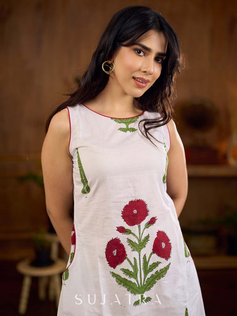 White sleeveless dress featuring red butta motifs and a gathered red panel at the hem, finished with coordinated red accents for a fresh, playful silhouette with a touch of traditional charm.