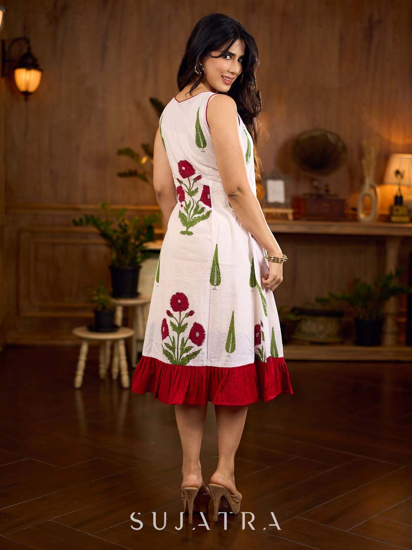 White sleeveless dress featuring red butta motifs and a gathered red panel at the hem, finished with coordinated red accents for a fresh, playful silhouette with a touch of traditional charm.