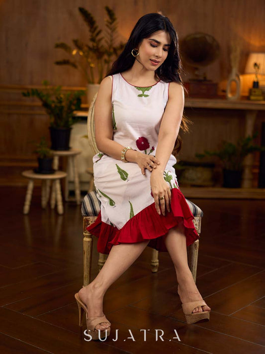 White sleeveless dress featuring red butta motifs and a gathered red panel at the hem, finished with coordinated red accents for a fresh, playful silhouette with a touch of traditional charm.