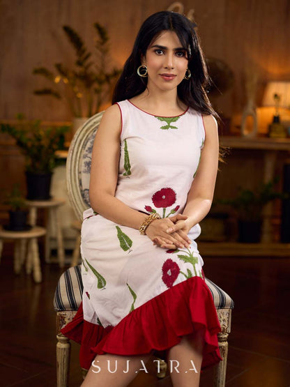 White sleeveless dress featuring red butta motifs and a gathered red panel at the hem, finished with coordinated red accents for a fresh, playful silhouette with a touch of traditional charm.