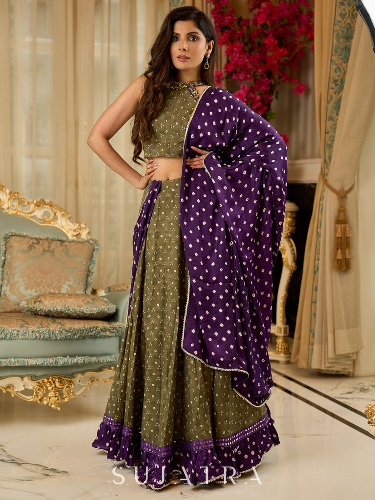 Vibrant Mehendi green and purple bandhani lehenga paired with a mirror work halter neck choli and matching dupatta.