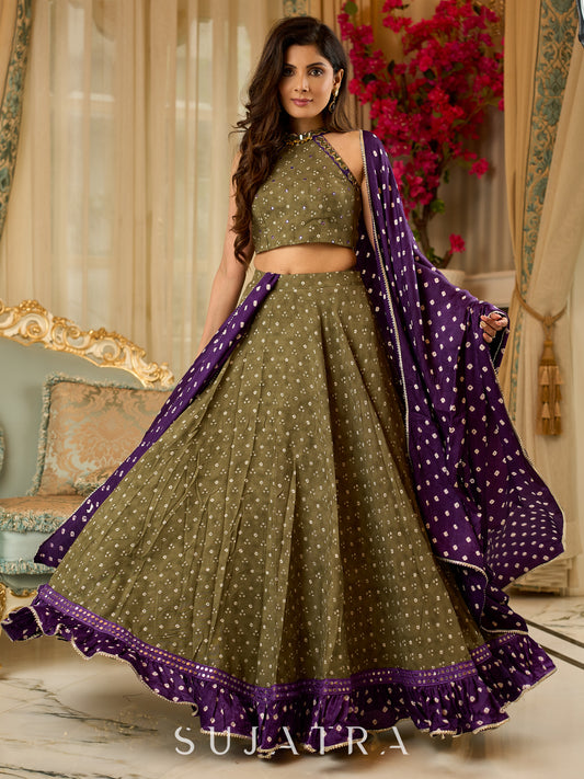 Vibrant Mehendi green and purple bandhani lehenga paired with a mirror work halter neck choli and matching dupatta.