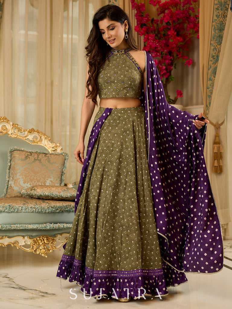 Vibrant Mehendi green and purple bandhani lehenga paired with a mirror work halter neck choli and matching dupatta.