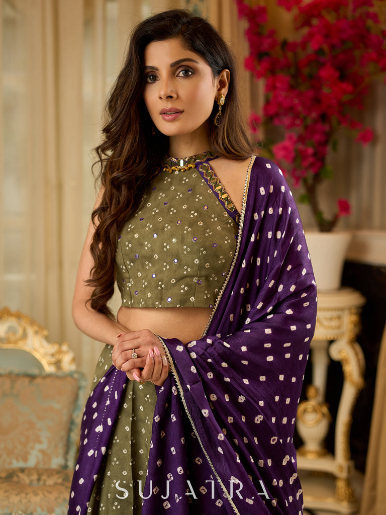 Vibrant Mehendi green and purple bandhani lehenga paired with a mirror work halter neck choli and matching dupatta.
