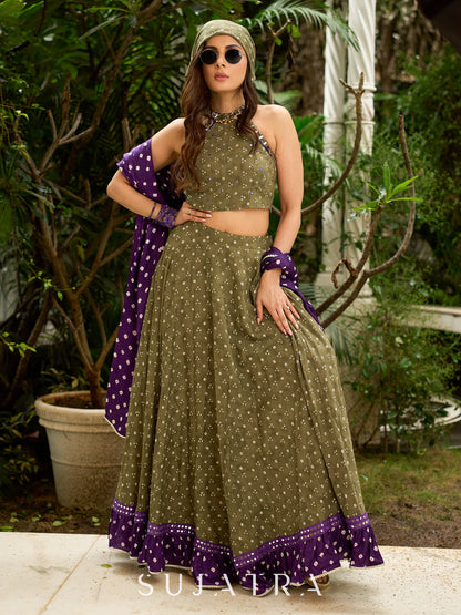 Vibrant Mehendi green and purple bandhani lehenga paired with a mirror work halter neck choli and matching dupatta.