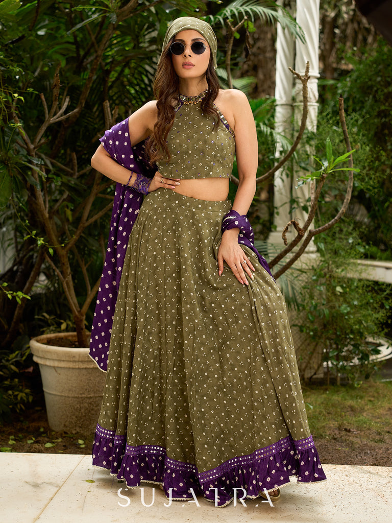 Vibrant Mehendi green and purple bandhani lehenga paired with a mirror work halter neck choli and matching dupatta.