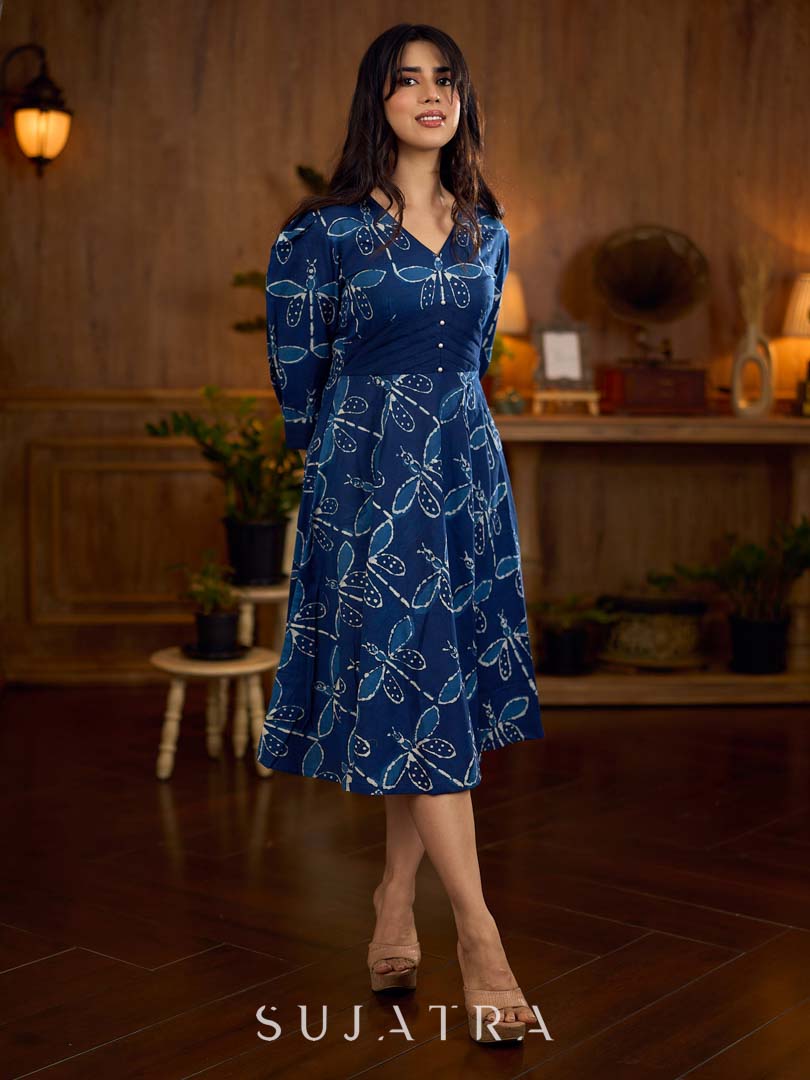 Indigo printed dress featuring dragonfly motifs, gathered sleeves with cuffs, and navy blue pleated waist detailing accented with pearls, creating a graceful silhouette with refined artisanal charm.