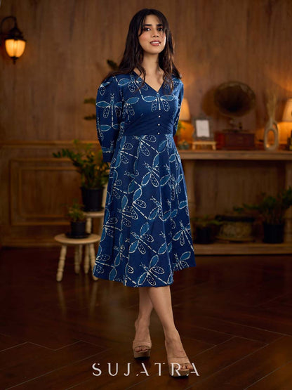 Indigo printed dress featuring dragonfly motifs, gathered sleeves with cuffs, and navy blue pleated waist detailing accented with pearls, creating a graceful silhouette with refined artisanal charm.