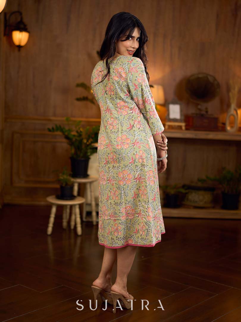 Soft green Gulmohar-printed dress featuring a square neckline and pearl-highlighted motifs, finished with an elasticated waist to create a flattering cinched silhouette with effortless charm.