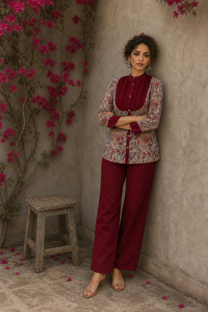 Elegant maroon floral top with intricate maroon pleats, high neckline, covered buttons, and coordinating sleeve cuffs.