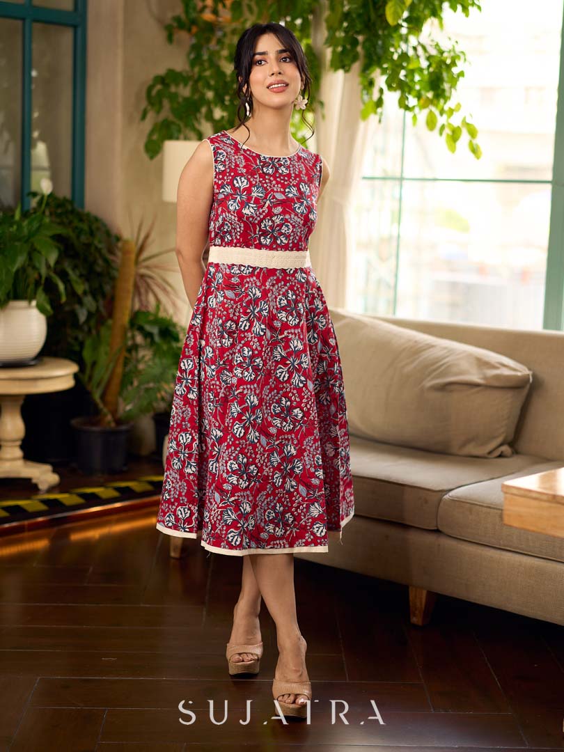 Red Gulmohar floral-printed sleeveless summer dress featuring off-white accents and scalloped lace detailing at the waist, creating a breezy, feminine silhouette perfect for warm, sunlit days.