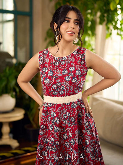 Red Gulmohar floral-printed sleeveless summer dress featuring off-white accents and scalloped lace detailing at the waist, creating a breezy, feminine silhouette perfect for warm, sunlit days.