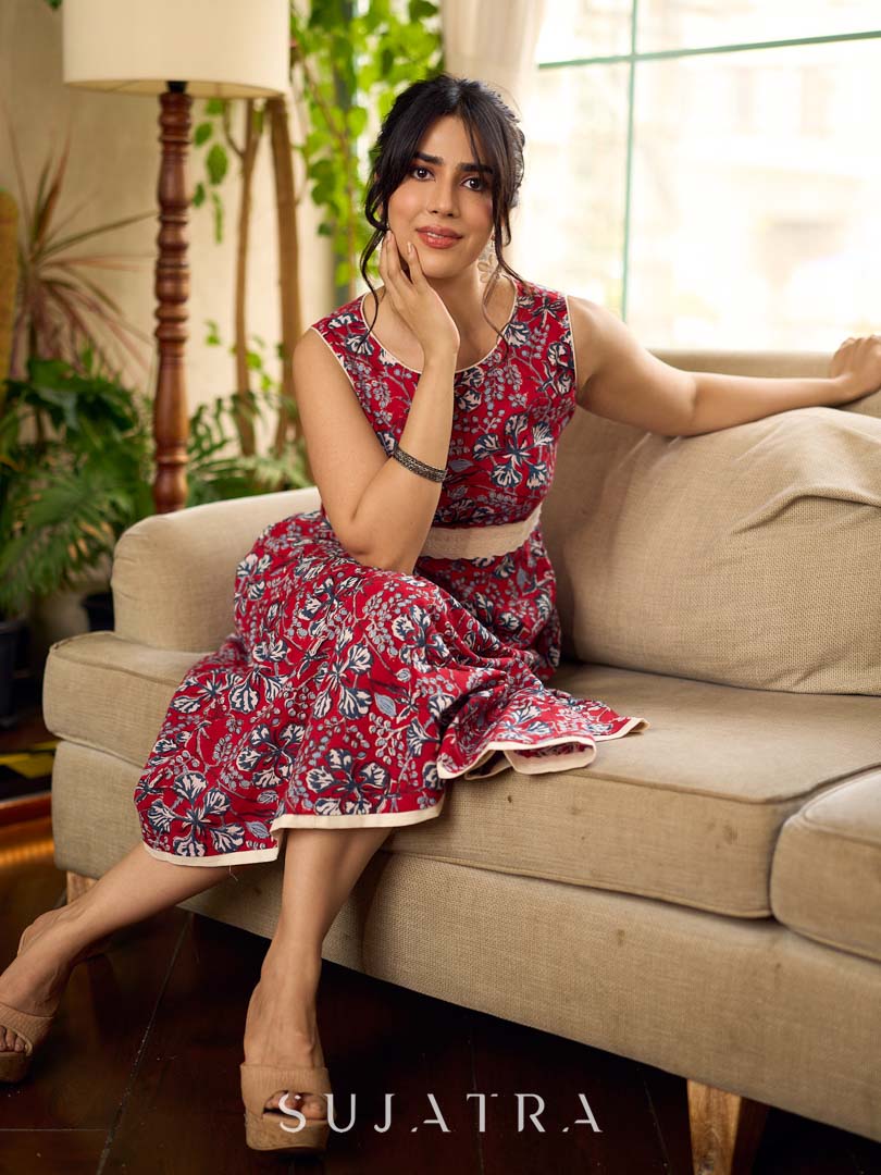 Red Gulmohar floral-printed sleeveless summer dress featuring off-white accents and scalloped lace detailing at the waist, creating a breezy, feminine silhouette perfect for warm, sunlit days.