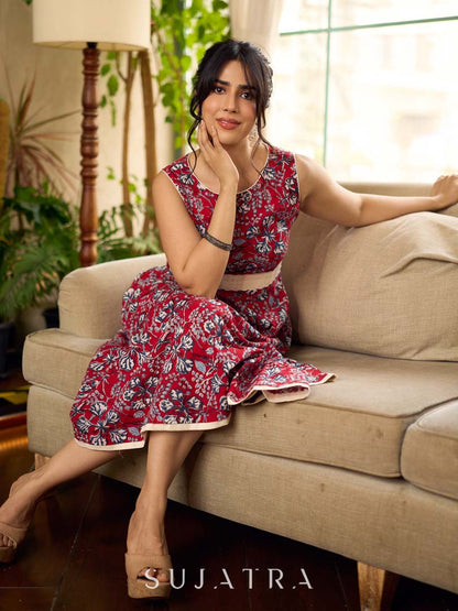 Red Gulmohar floral-printed sleeveless summer dress featuring off-white accents and scalloped lace detailing at the waist, creating a breezy, feminine silhouette perfect for warm, sunlit days.