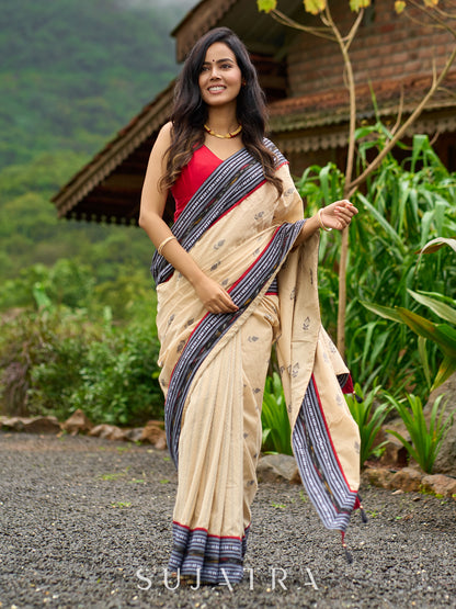 Beige cotton saree enriched with traditional Ikat border and Jamdani accents