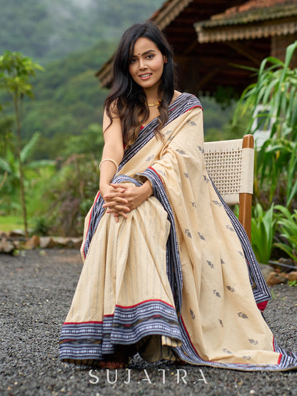Beige cotton saree enriched with traditional Ikat border and Jamdani accents
