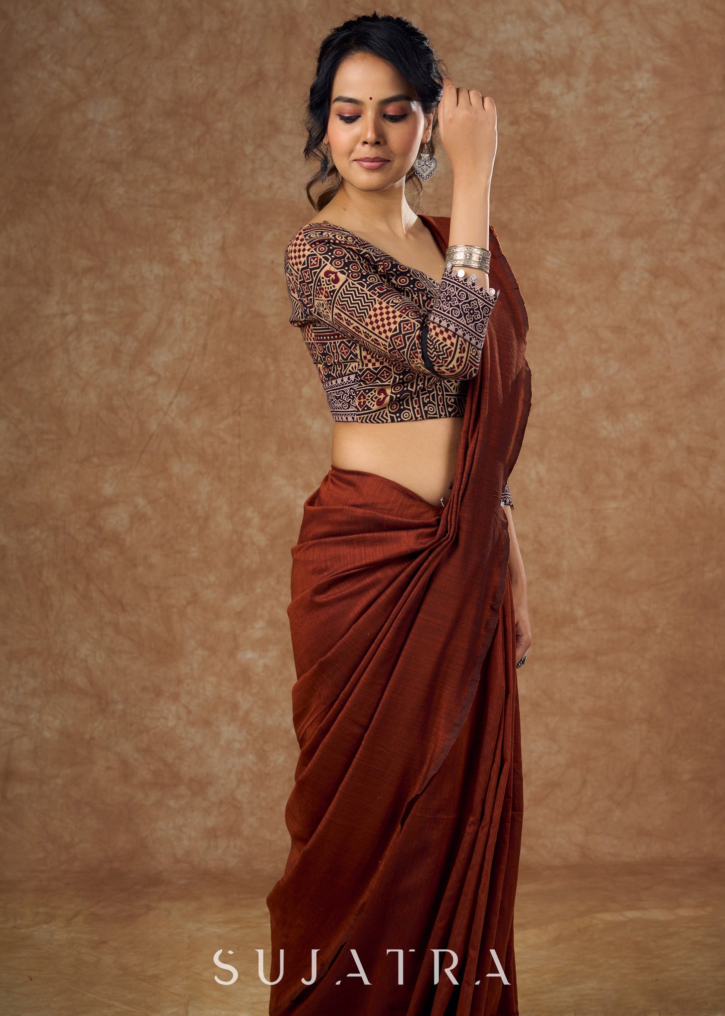 Striking half and half Ajrakh blouse combining maroon & black hues elevated by intricate coin work .
