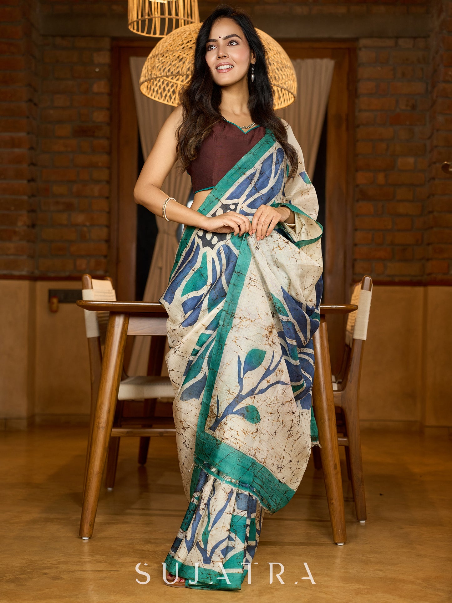 Classic ivory pure silk saree highlighted by teal borders and hand batik artistry