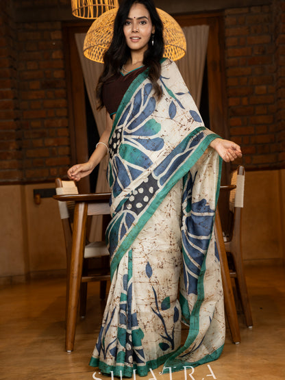 Classic ivory pure silk saree highlighted by teal borders and hand batik artistry