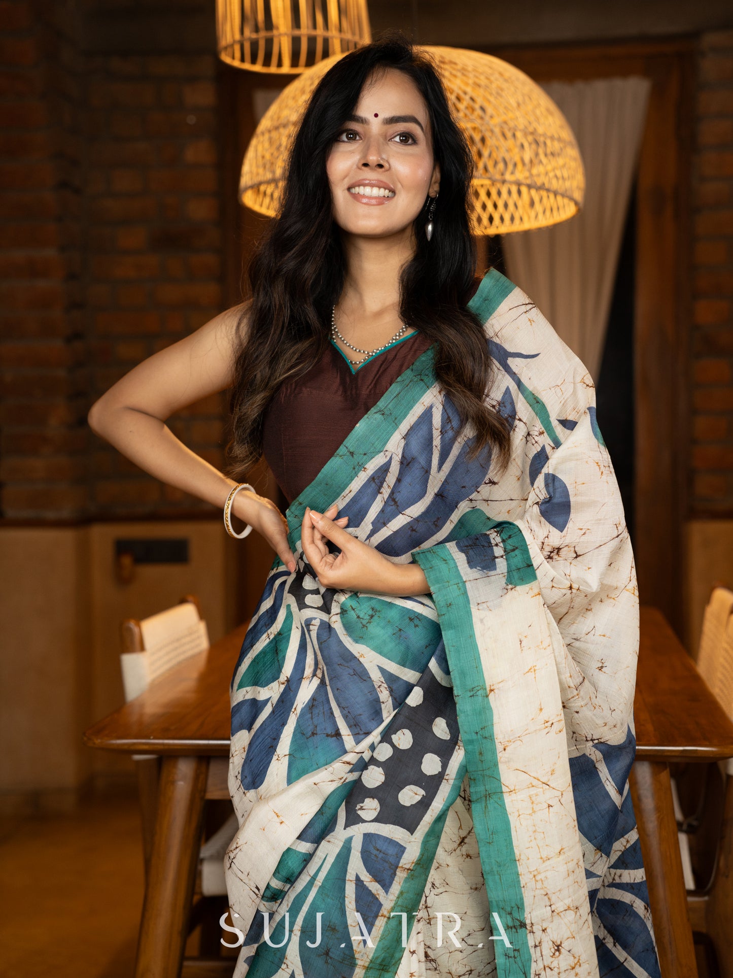 Classic ivory pure silk saree highlighted by teal borders and hand batik artistry