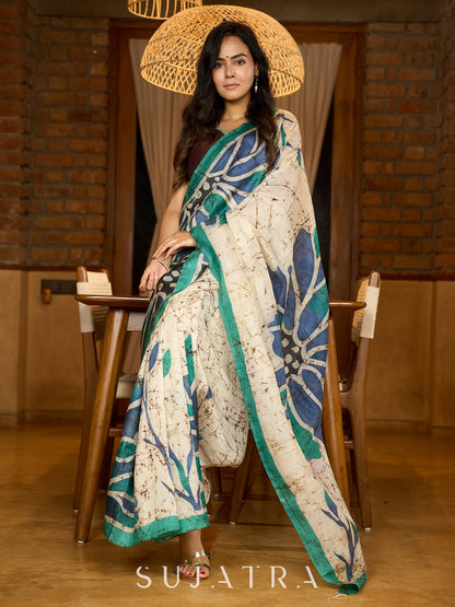 Classic ivory pure silk saree highlighted by teal borders and hand batik artistry